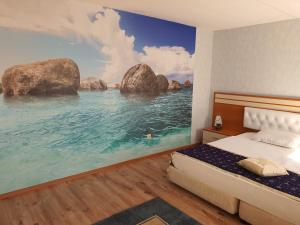 a bedroom with a painting of the ocean at Hotel Dobrudja in Dobrich