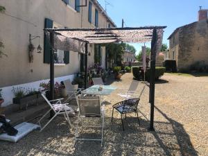un patio con mesa y sillas bajo una pérgola en La Revaudiere en Bressuire