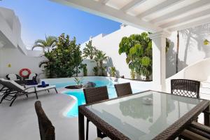 a patio with a table and chairs and a swimming pool at Villa 87 in Corralejo