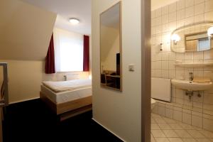 ein Bad mit einem Bett, einem Waschbecken und einem Spiegel in der Unterkunft Hotel Stadt Kamen in Kamen