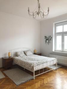 ein weißes Schlafzimmer mit einem Bett und einem Kronleuchter in der Unterkunft Apartamenty Zasanie in Przemyśl