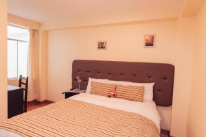 - une chambre avec un grand lit et une tête de lit marron dans l'établissement Hotel Las Quenas, à Cusco