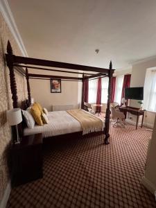 a bedroom with a canopy bed in a room with a piano at Haley's Hotel in Leeds