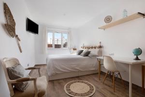 a white bedroom with a bed and a desk at Villa del Relax in Corralejo