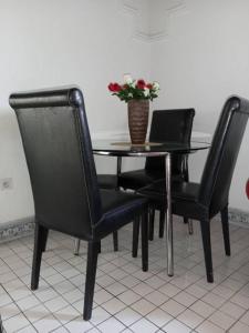 een tafel met twee zwarte stoelen en een vaas met bloemen bij Beautiful appartement 2 beds 2 toilets kitchen in Bonamakolo
