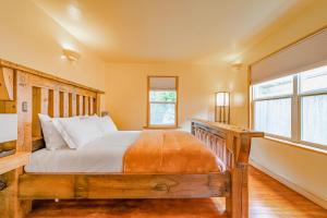 a bedroom with a wooden bed and two windows at El Nido The Nest in Arcata