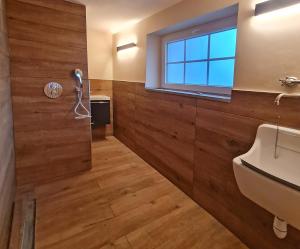 a bathroom with wooden walls and a sink and a window at Maison 1775 Ferien im historischen Bauernhaus mit Sauna, Wissembourg, Elsass in Ingolsheim