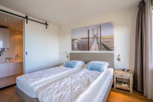 ein Schlafzimmer mit einem großen weißen Bett mit blauen Kissen in der Unterkunft Appartementencomplex Juliana 122 in De Koog