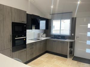 a kitchen with wooden cabinets and a sink and a microwave at Loft atlantique Rochefort in Rochefort