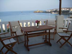 a wooden table on a balcony with a view of the ocean at Vassiliki Studios in Andros