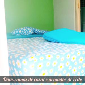 a bed with a blue comforter with flowers on it at Chalés Mariza in Luis Correia