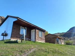 una antigua casa de madera en una colina con montañas en el fondo en Complejo Las Maras II en El Chaltén