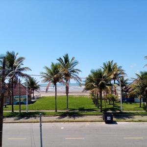 una calle vacía con palmeras y una playa en Apto Aluguel na Temporada Pé na Areia Peruíbe SP en Peruíbe