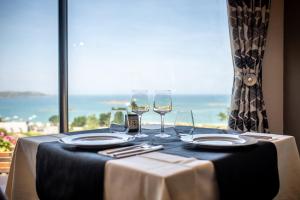 - une table avec des verres à vin et une vue sur l'océan dans l'établissement Domaine Buhez Nevez, à Trélévern