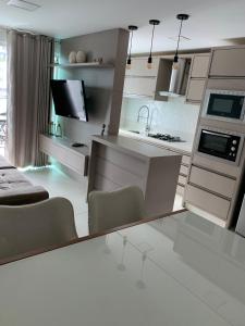 una cucina con armadi bianchi, tavolo e sedie di Encanto dos Mares - Apartamento premium 4 a Camboriú