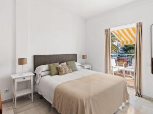 a white bedroom with a large bed and a balcony at Ático de 2 dormitorios en Andalucía del mar in Marbella
