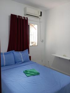ein Schlafzimmer mit einem blauen Bett und einem grünen Handtuch darauf in der Unterkunft Condominio Oliveira in Maragogi