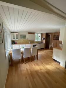 a kitchen with a dining table and white chairs at Ljunghusen Holiday Inn Cottage in Ljunghusen