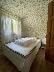 ein Schlafzimmer mit einem Bett in einem Zimmer mit einem Fenster in der Unterkunft Ljunghusen Holiday Inn Cottage in Ljunghusen