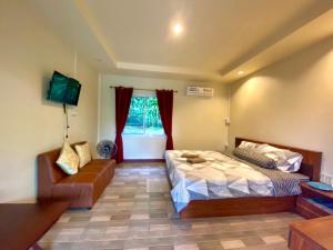 een slaapkamer met een bed en een bank bij นพรัตน์การ์เด้นฮิลล์ in Uthai Thani