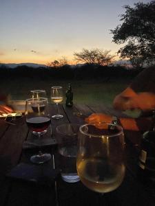a wooden table with glasses of wine on it at Sunset Lodge & Safaris in Guernsey Nature Reserve