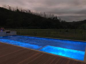 a large blue swimming pool with a wooden deck at Espaço Casa na Rocha in São José dos Campos