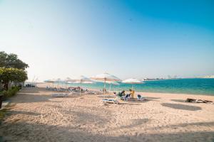 uma praia com cadeiras e guarda-sóis e o oceano em 1-bedroom apartment with pool em Dubai