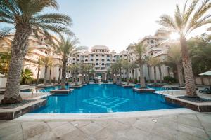 uma grande piscina com palmeiras em frente a um edifício em 1-bedroom apartment with pool em Dubai