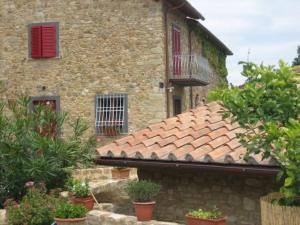 un ancien bâtiment en pierre avec des fenêtres rouges et des plantes dans l'établissement Agriturismo Casa Belvedere, à Bacchereto