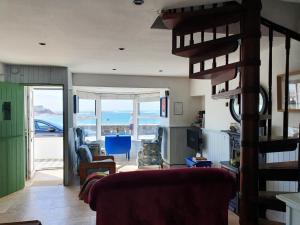 a living room with a spiral staircase with a view of the ocean at Sea Warrior Cottage in Kilkee