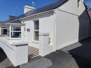 a white building with a door and a window at Sea Warrior Cottage in Kilkee