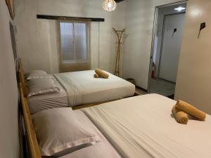 a bedroom with two beds and a mirror at Layang Layang Guest House Melaka in Melaka