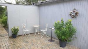 a patio with chairs and a table and some plants at Ferienwohnungen Hachenberger in Langenhorn