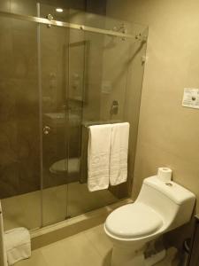 a bathroom with a toilet and a shower with towels at Hotel Raymipampa in Cuenca
