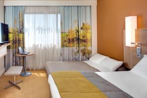 a hotel room with two beds and a window at Hôtel Mercure Mâcon Bord de Saône in Mâcon