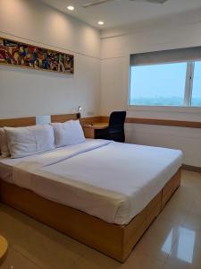 a bedroom with a bed and a desk and a window at Mango Grove Hotel in Chandīgarh