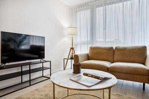 a living room with a couch and a tv at Olympia Homes beautifully furnished flats in Epalinges