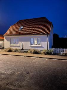 una casa blanca con techo rojo en una calle en Løkke-bo, en Løkken