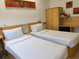 2 letti in camera d'albergo con lenzuola bianche di Mango Grove Hotel a Chandīgarh