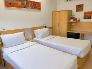 2 bedden in een hotelkamer met witte lakens bij Mango Grove Hotel in Chandīgarh