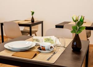 una mesa con platos y un jarrón de flores. en B Home Apart Hotel by Alpha, en Bogen