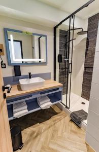 La salle de bains est pourvue d'un lavabo et d'une douche. dans l'établissement Logis Hôtel du Parc, à Perros-Guirec