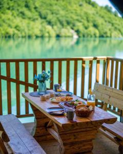 a picnic table with food and a view of a lake at Glamping Bagrem in Jablanica