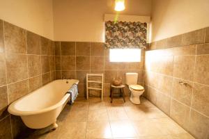 a bathroom with a tub and a toilet and a sink at The Townhouse in Graaff-Reinet