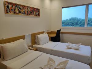 a hotel room with two beds and a window at Mango Grove Hotel in Chandīgarh