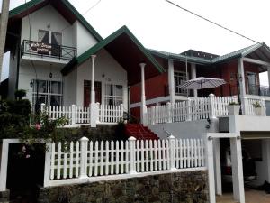 a white picket fence in front of a house at Winter Dream Holiday Bungalow Nuwara Eliya in Nuwara Eliya