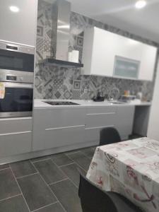 uma cozinha com armários brancos e uma mesa com uma toalha de mesa em Lisbon, 3 bedroom apartment in Amora , 15 min from the beach em Amora