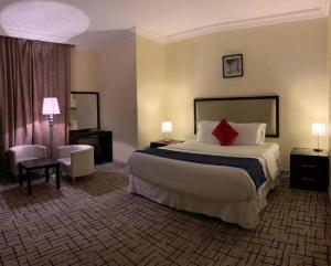 una camera d'albergo con un grande letto con cuscino rosso di فندق البروج a Jazan