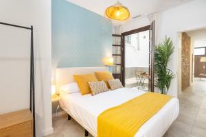 Un dormitorio con una cama grande con una manta amarilla. en Apartamentos Luna Suites Palacio Dorita, en Granada