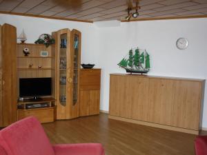 a living room with a television and wooden cabinets at Meerblick 424 im Haus Trafalgar in Cuxhaven
